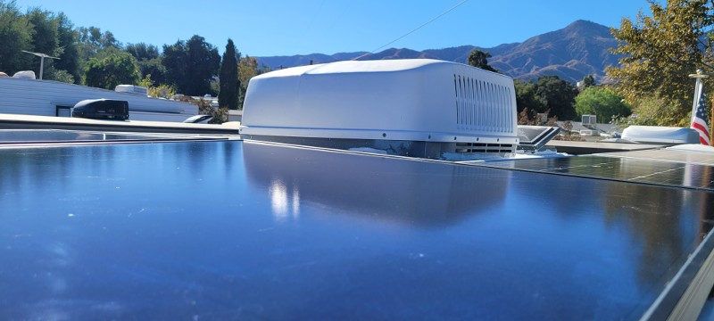 The top of an RV with a solar panel and air conditioning unit.