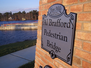 An information plaque on brick for AJ Brafford Pedestrian Bridge.