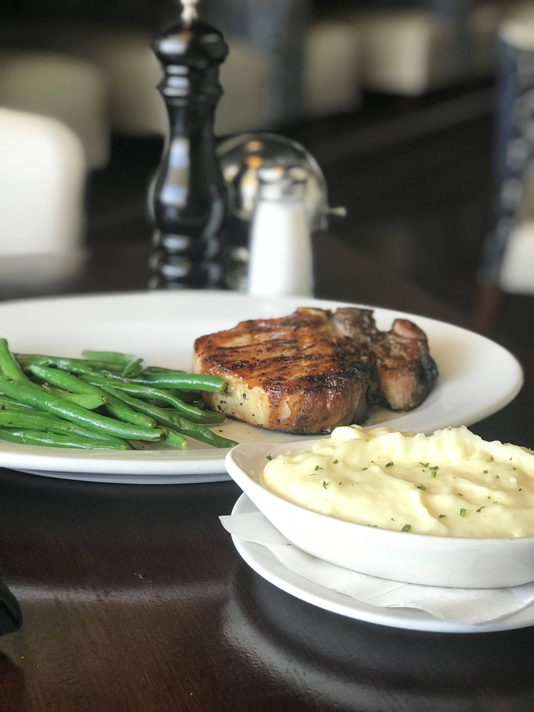 Glazed pork chop with green beans and mashed potatoes.