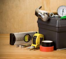 A toolbox is surrounded by a hammer, level, tape measure, wrench, tape, and pressure gauge.