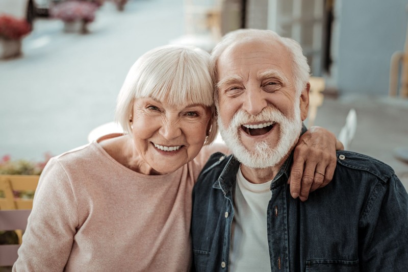 Senior couple putting their arms around one another.