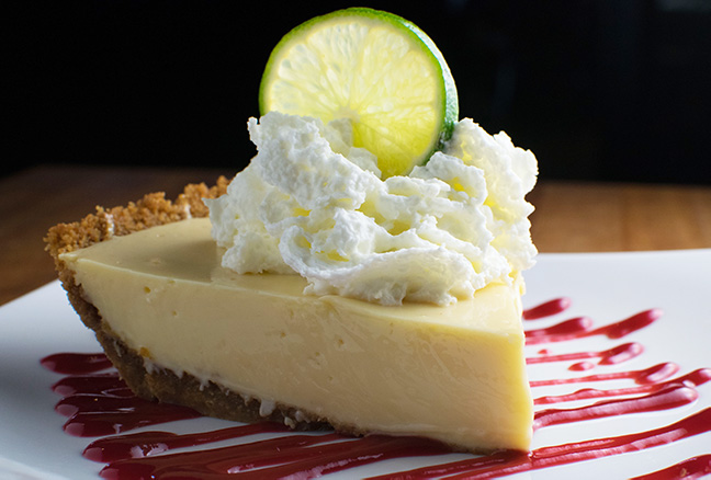 Generous slice of key lime pie topped with whipped cream.