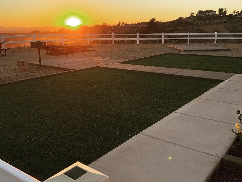 A green yard surrounded by a concrete sidewalk.