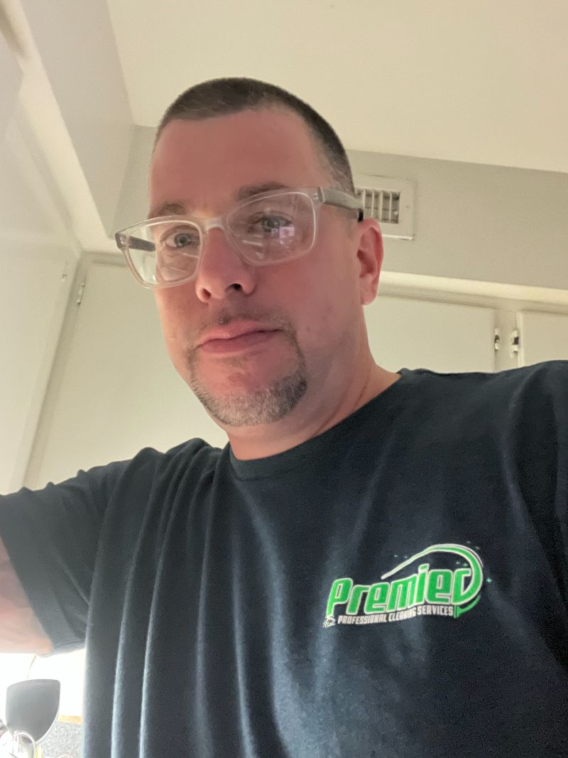 The closeup of a man wearing glasses and a T-shirt for Premier Professional Cleaning Services.