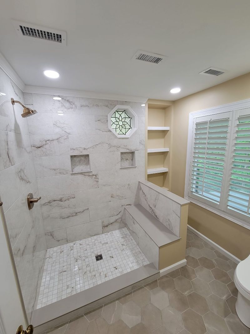 A bathroom makeover with open tile shower and tile flooring.