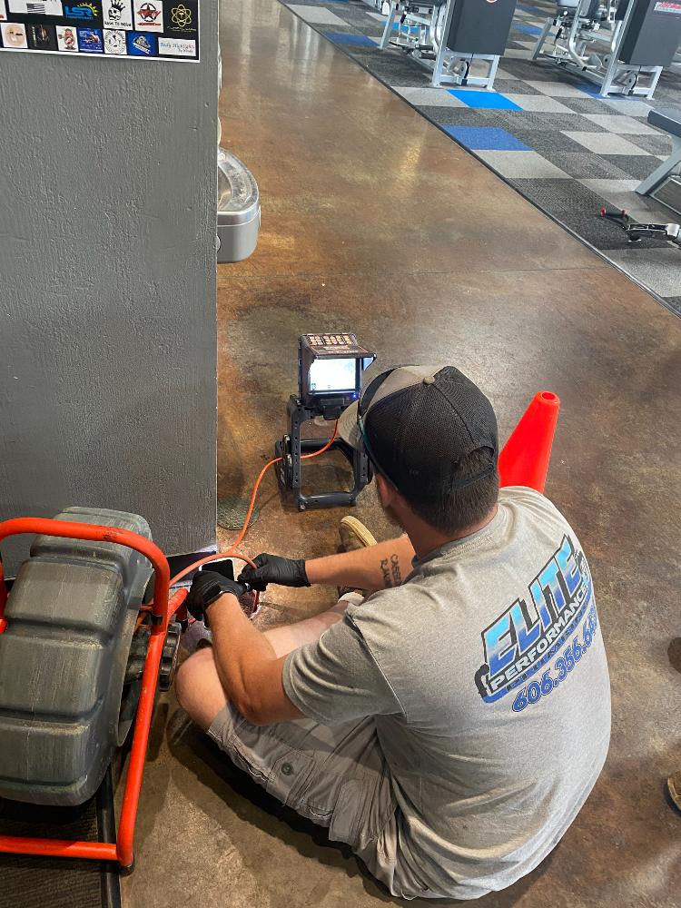 Plumber fixes water fountain inside of a public gym
