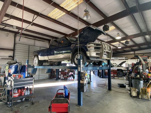 A blue pickup truck is raised on a lift for repairs.