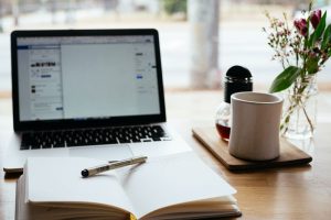 laptop screen with a book in front of it with a cup of coffee