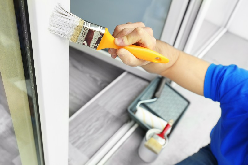 Young man painting window at home