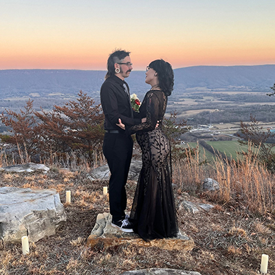 A bride and groom look at each other with valley scene in the background.