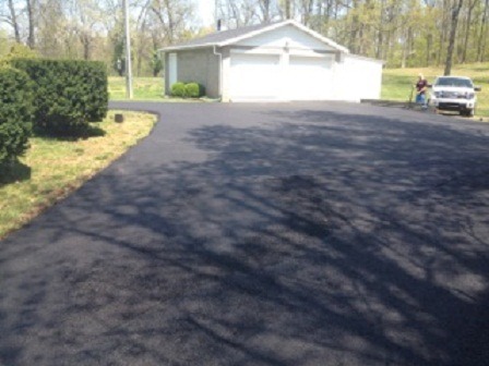 An asphalt driveway leads to a two-care garage.