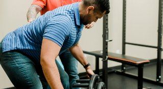 A patient squats down to chiropractic equipment.