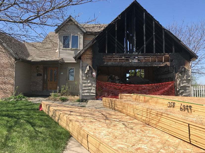 Stacks of lumber lie near a burned-out garage of a home.