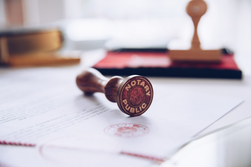 A notary public stamp rests on top of legal documents.