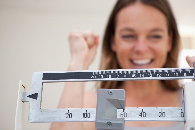 A woman smiles while looking at a scales.