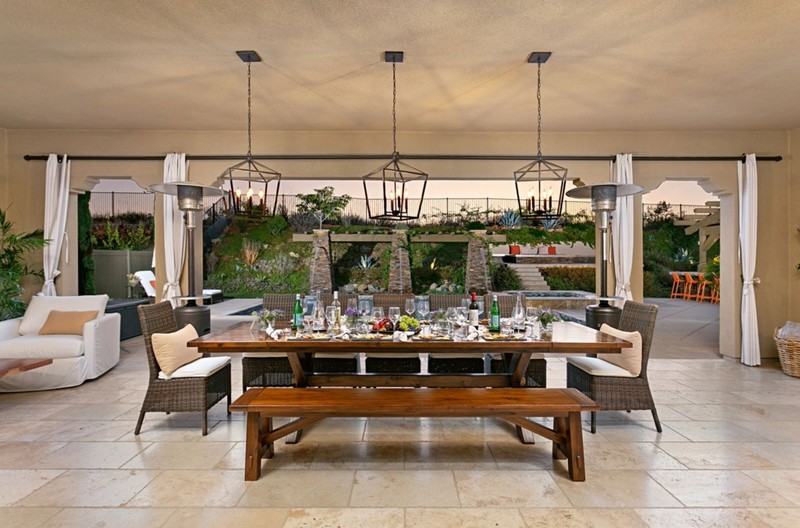 Outdoor dining space with tile floor, farm table, bench seating, and canvas cover
