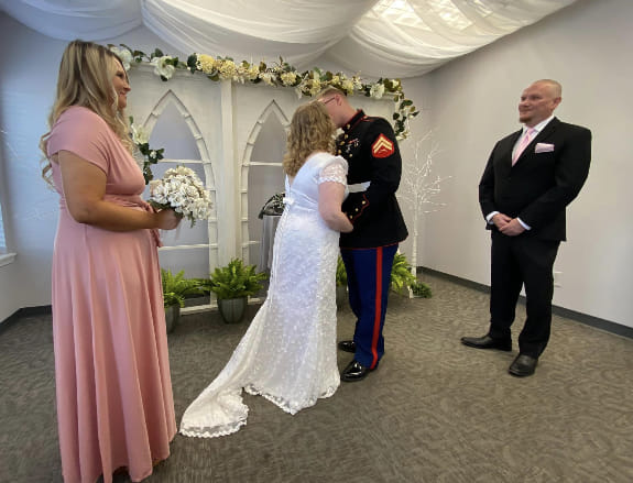 A military groom and bride kiss at their ceremony.