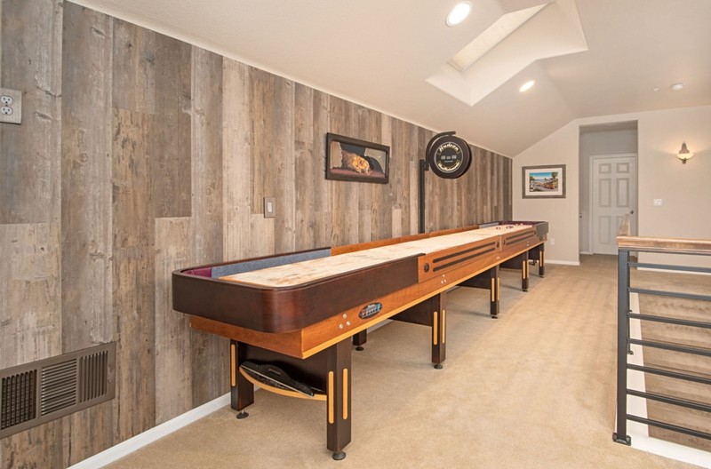 game room with shuffleboard table, wood paneled walls, light carpet