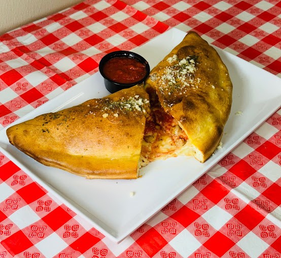 A piping hot calzone stuffed with cheese, marinara, and pepperoni, served with a side or marinara for dipping