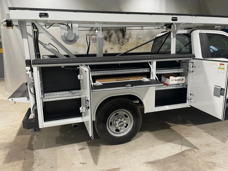 White company pickup with several tool storage boxes built into the sides.