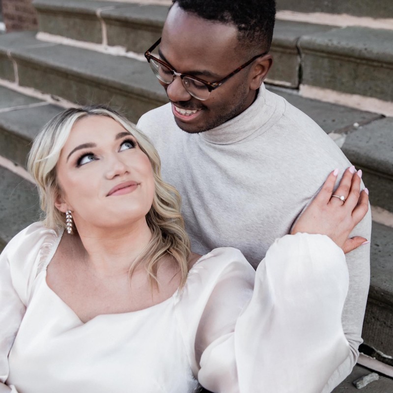 A man looks down at a woman sitting in front of him.