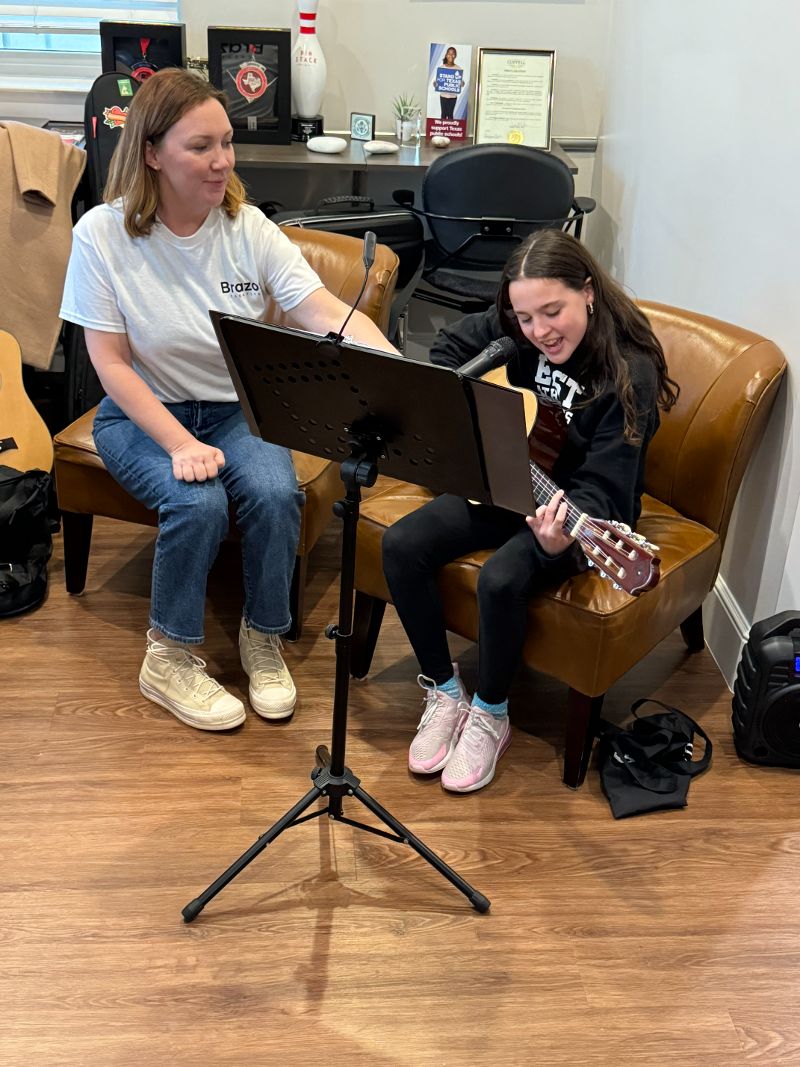 Instructor teaching a young girl guitar.