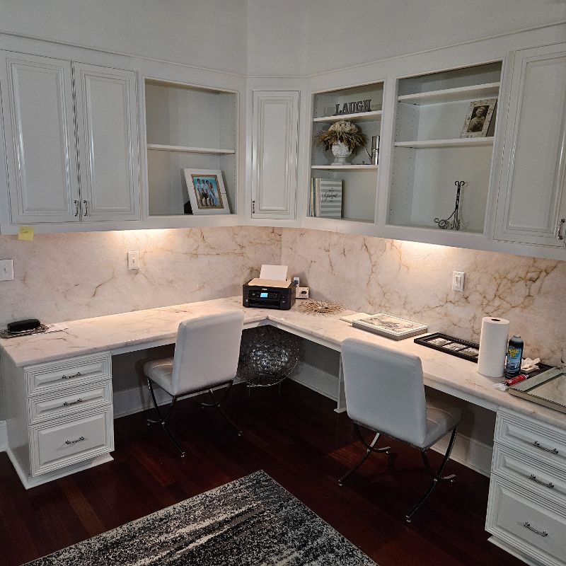 A corner desk with a granite countertop and backsplash.