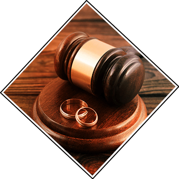 A wooden gavel rests on a desk next to two wedding rings