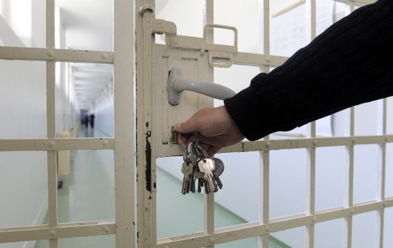 Prison guard opens a cell block door with a large ring of keys.