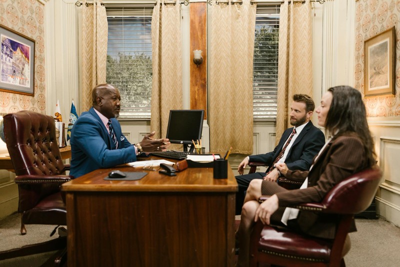 three people sitting at a desk in a meeting