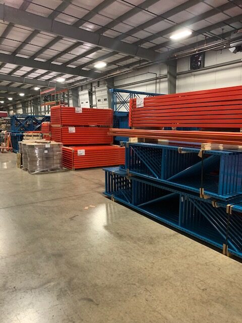 Stacks of pallet racking material sit in a warehouse.