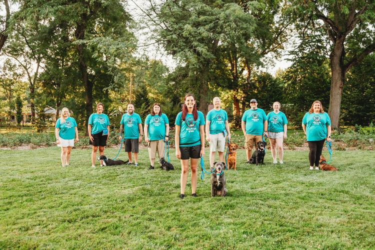 Lindsay Stamper poses for a photo with her staff and numerous dogs.