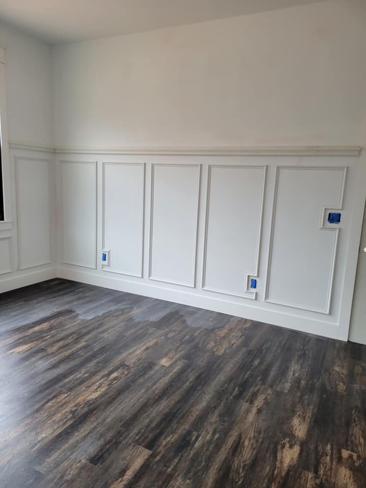 A newly painted dining room with white walls and dark laminate flooring.