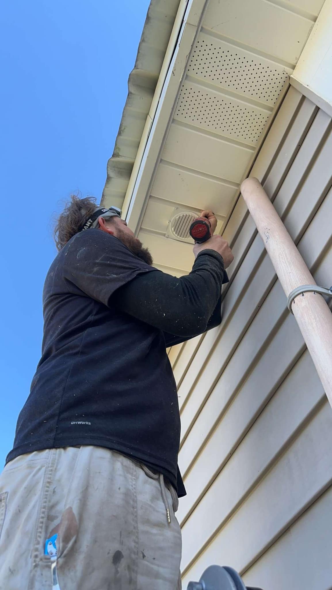 A man secures soffit on a home’s roof.