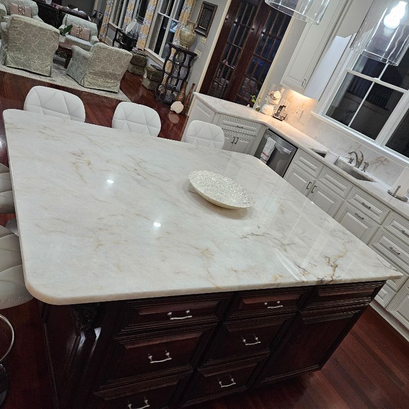 A square kitchen island with a marble countertop.