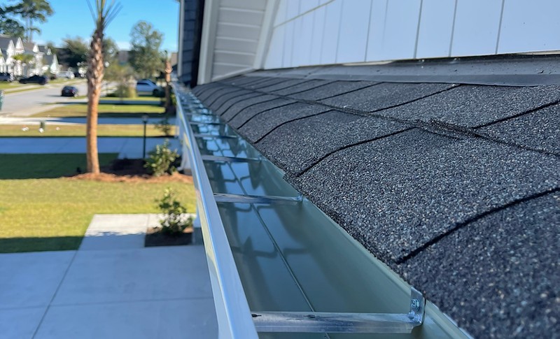 A metal gutter system attached to a shingled roof.