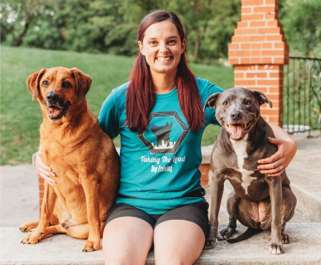 Lindsay Stamper smiles while posing with two dogs.