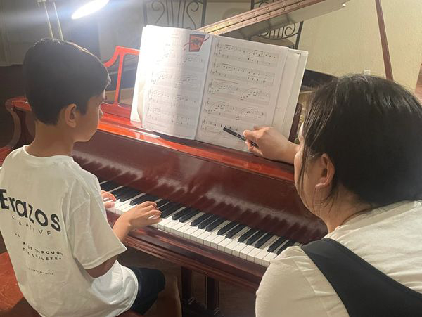 Piano instructor teaching  a young student piano.