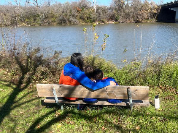 Stephanie Syphus sitting on a bench with her kids looking out over a river.