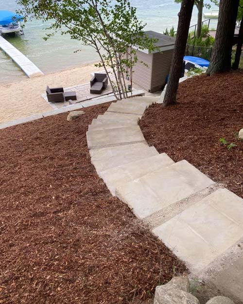 A beautiful concrete stairway meandering down a freshly mulched hill.
