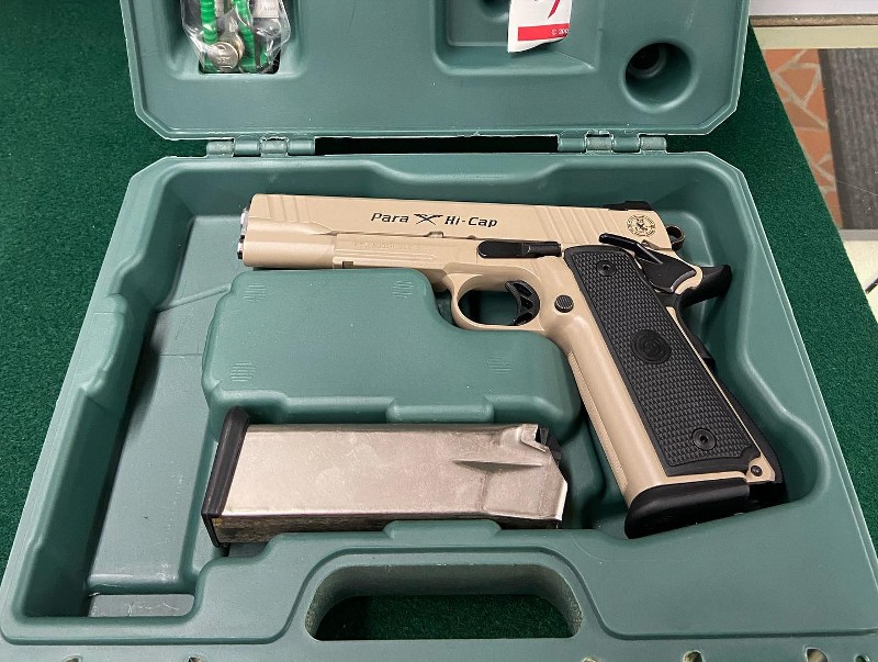 A tan-colored handgun with magazine sits in a green case.