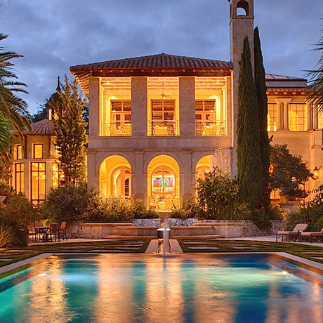 backyard inground pool area with multi-story house light up in the background