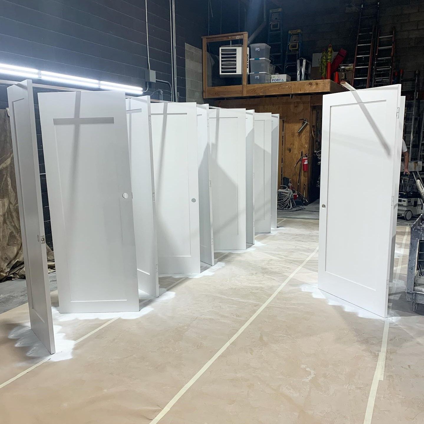 Freshly painted white doors lined up in a workshop.