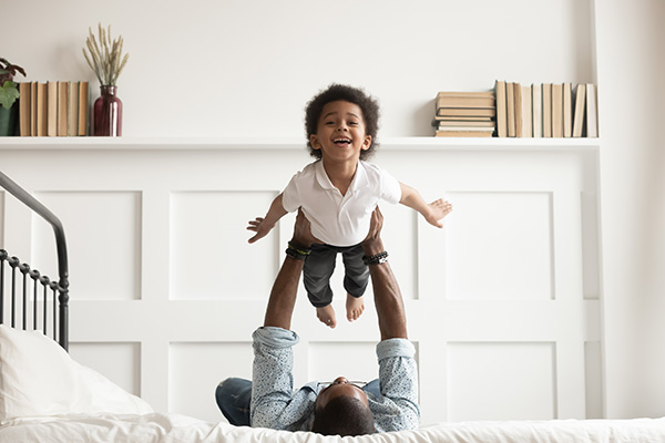 Man holds a smiling child above him in the air