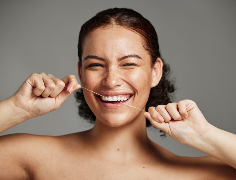 A woman smiles while flossing