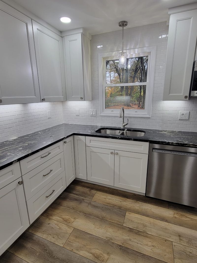 A handsome kitchen makeover with white cabinetry, luxury vinyl flooring, and modern backsplash.