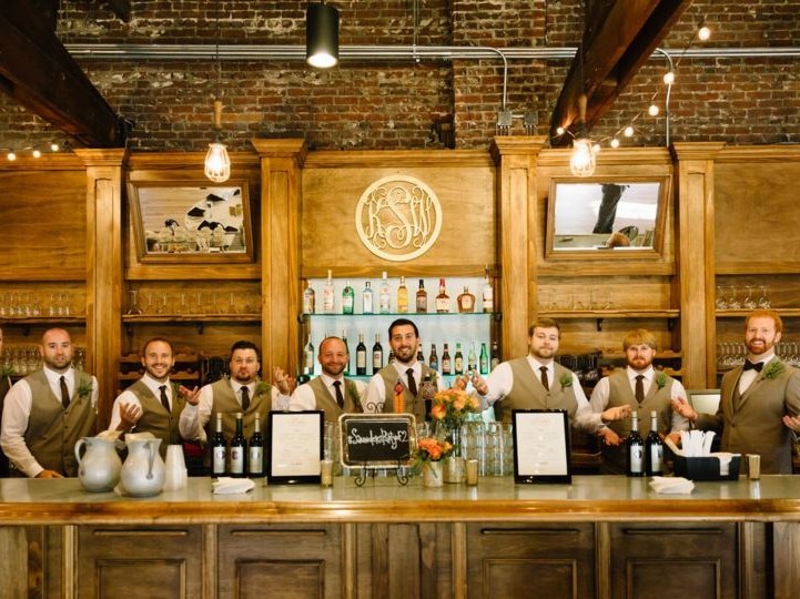 Bar staff stand behind antique bar, ready to serve