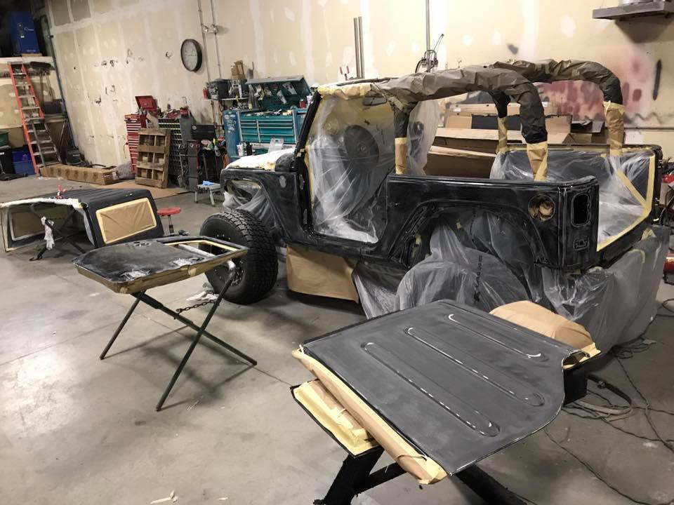A utility vehicle sits in a shop masked and ready for spray coating.