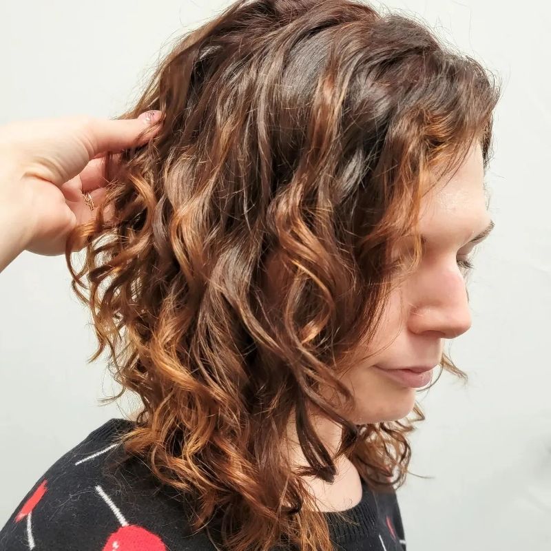A young woman with wavy reddish brown hair shows off her new style