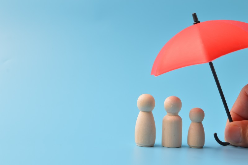 Small umbrella sheltering wooden figurines.